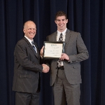 Doctor Potteiger posing for a photo with an award recipient  in a grey suit and black and white plaid tie